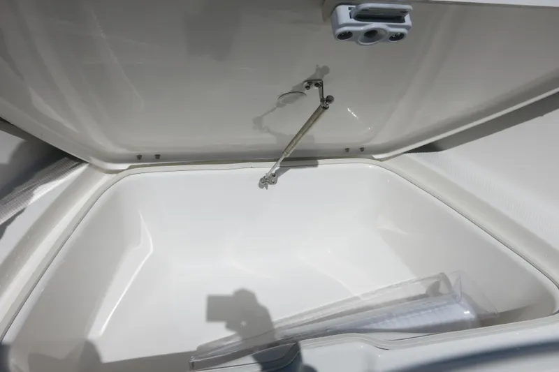Slide: The Image of 2026 Robalo R180 Center Console storage compartment, open lid, white interior. - 12