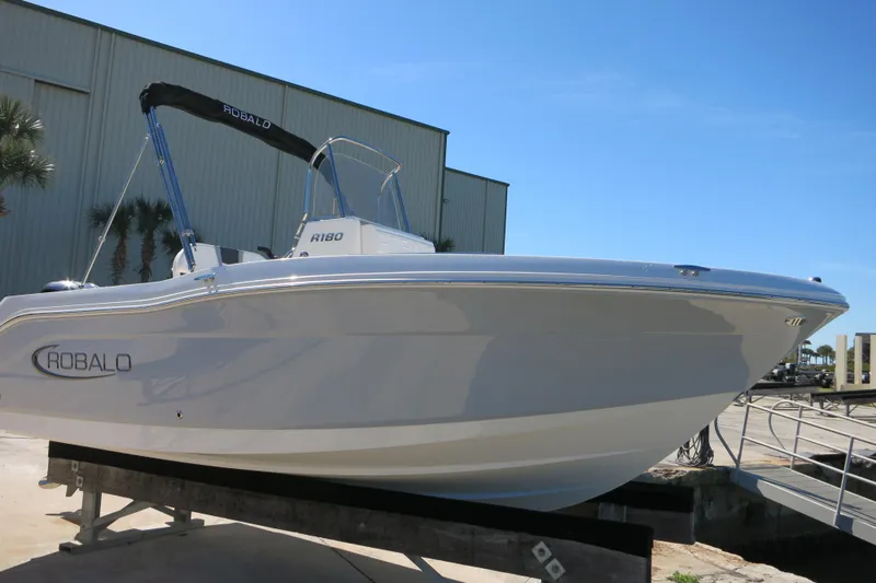 Slide: The Image of 2026 Robalo R180 Center Console boat displayed outdoors on a sunny day. - 2