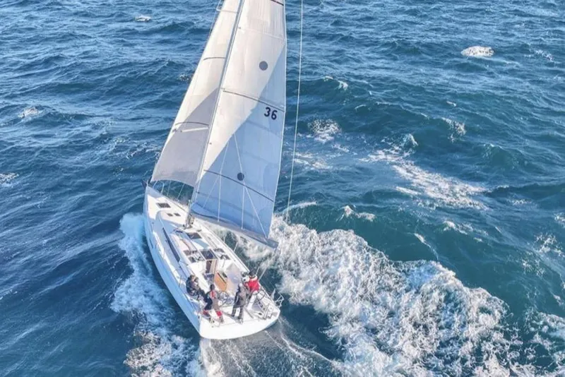 The Image of 2023 Beneteau First 36 sailboat navigating through ocean waves, aerial view. - 0