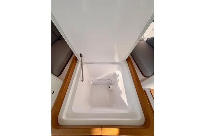 Slide: The Image of 2023 Beneteau First 36 interior storage compartment with wooden trim and seating area. - 58