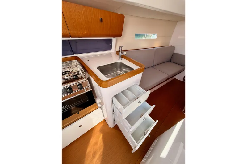 Slide: The Image of 2023 Beneteau First 36 yacht interior with kitchen, sink, stove, and seating area. - 60