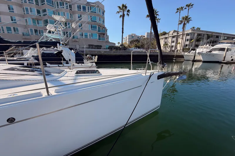 Slide: The Image of 2023 Beneteau First 36 yacht docked in a marina with modern buildings. - 8