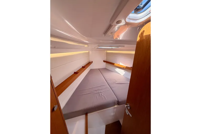 Slide: The Image of 2023 Beneteau First 36 cabin interior with cozy bed and wooden accents. - 85