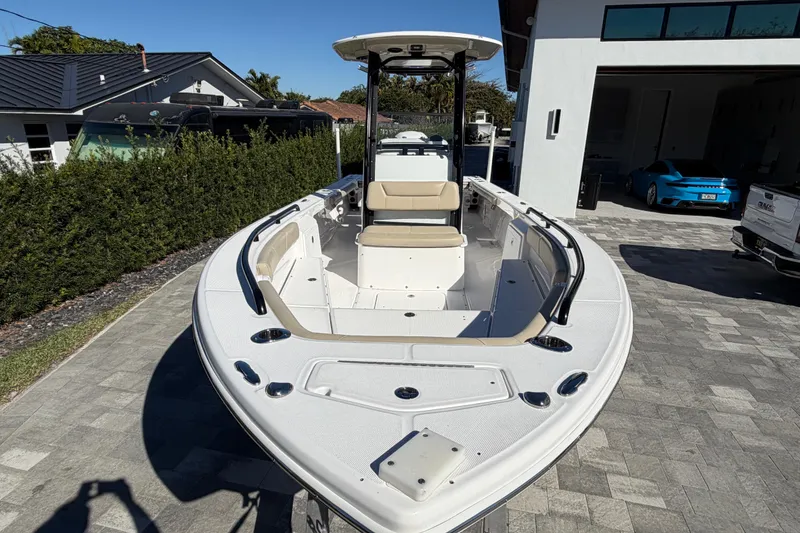 Slide: The Image of 2019 Everglades 243 Center Console boat parked in a driveway, surrounded by greenery. - 5