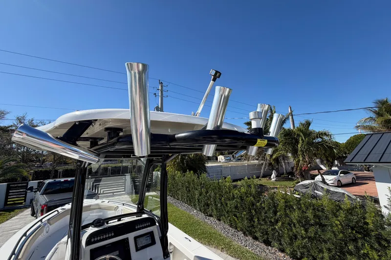 Slide: The Image of 2019 Everglades 243 Center Console boat with rod holders, parked outdoors under clear blue sky. - 7