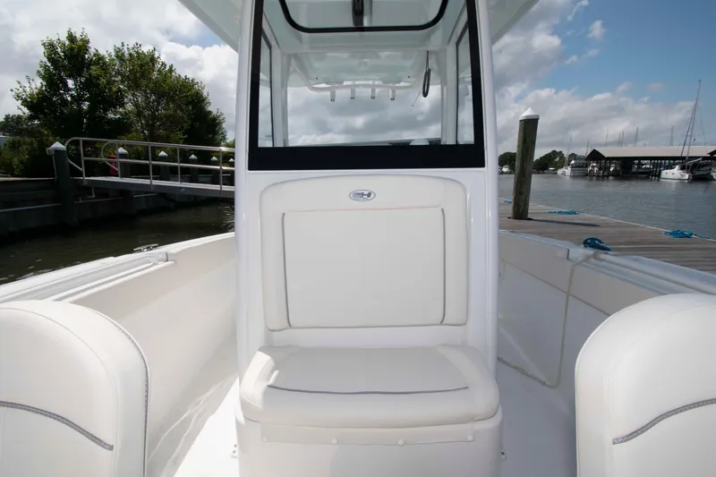 Slide: The Image of 2023 Sea Hunt Ultra 265 SE boat interior, featuring white seating and console, docked by the water. - 4