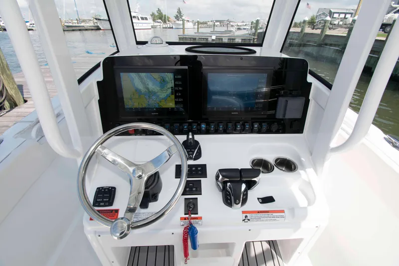 Slide: The Image of 2023 Sea Hunt Ultra 265 SE boat dashboard with steering wheel and navigation screens. - 7