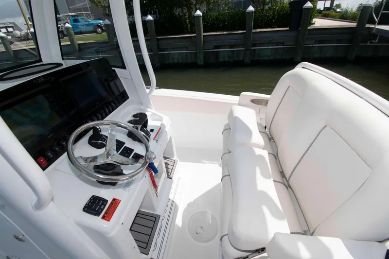 Slide: The Image of 2023 Sea Hunt Ultra 265 SE boat interior with steering wheel and white seating. - 8