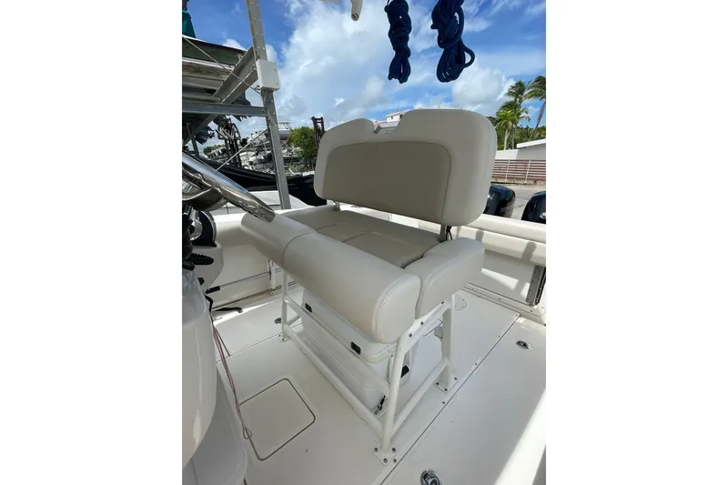 Slide: The Image of Boston Whaler 230 Outrage 2021 boat seat, white upholstery, sunny day, palm trees in background. - 10
