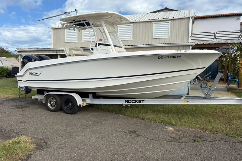 Slide: The Image of 2021 Boston Whaler 230 Outrage boat on a trailer, parked outdoors. - 14