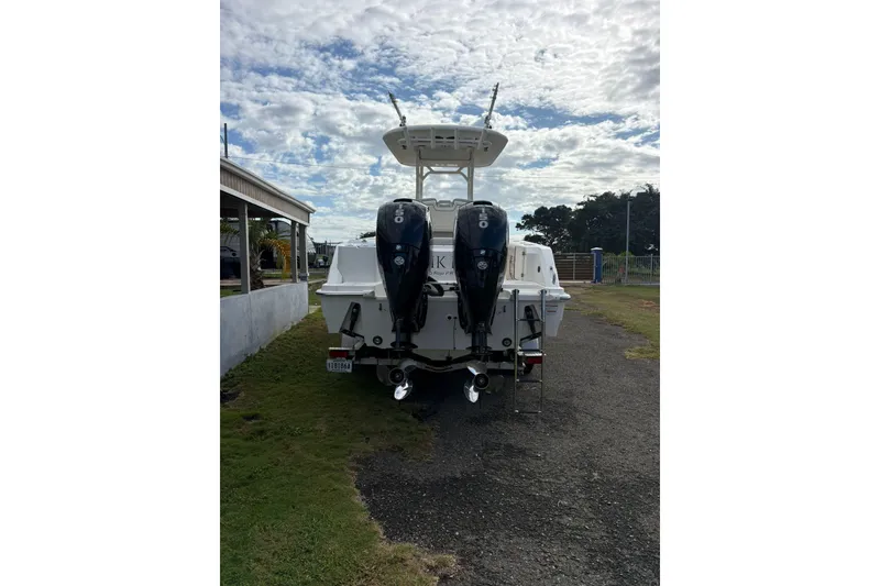 Slide: The Image of 2021 Boston Whaler 230 Outrage with dual outboard engines, parked on a grassy area. - 3