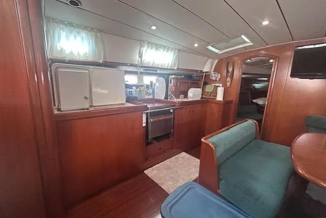 Slide: The Image of Interior of 2001 Beneteau Oceanis 461 yacht, featuring a cozy kitchen and dining area. - 15