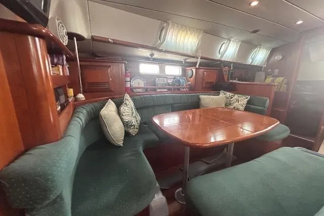Slide: The Image of Interior of 2001 Beneteau Oceanis 461 yacht with green seating and wooden table. - 25