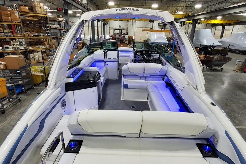 Slide: The Image of 2020 Formula 310 Bowrider boat interior with blue LED lighting in a warehouse setting. - 43