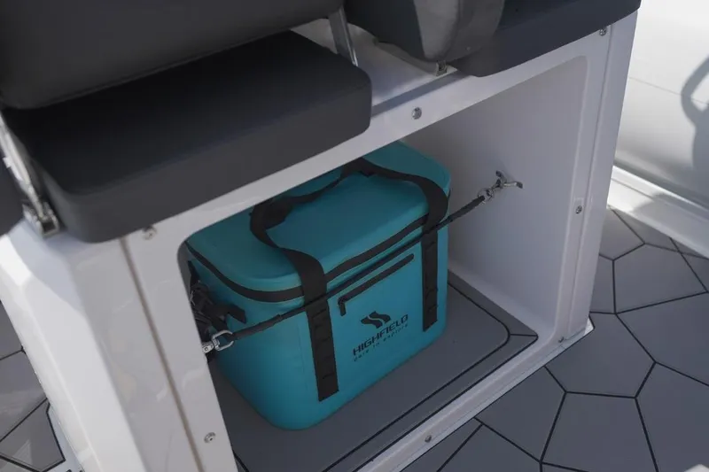 Slide: The Image of 2026 Highfield Sport 660 boat storage with a blue cooler secured inside. - 6