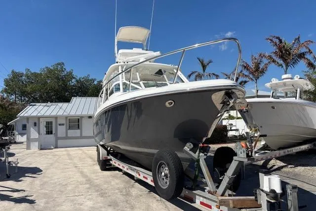 Slide: The Image of 2008 Everglades 350LX boat on trailer, parked near a small building, under clear blue sky. - 2