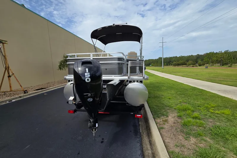 Slide: The Image of 2026 Sun Tracker Sportfish 24 XP3 pontoon boat with 150 HP engine, parked outdoors. - 93