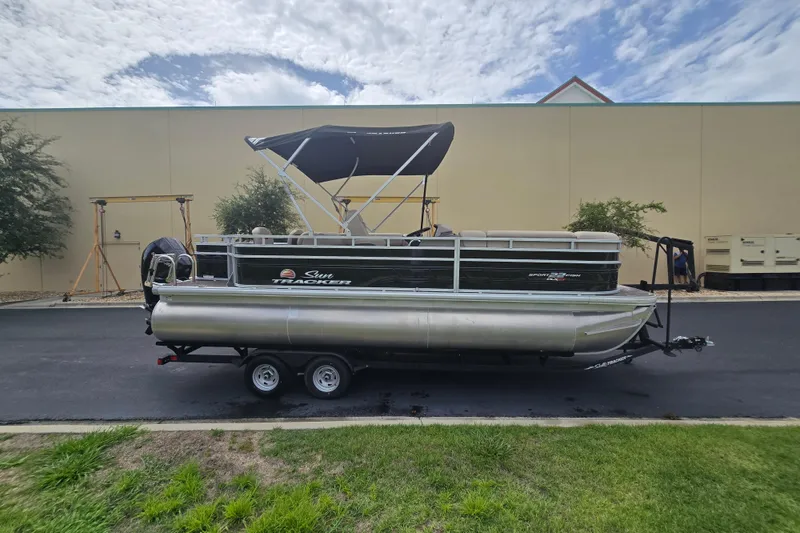 Slide: The Image of 2026 Sun Tracker Sportfish 24 XP3 pontoon boat on trailer, parked outdoors. - 85