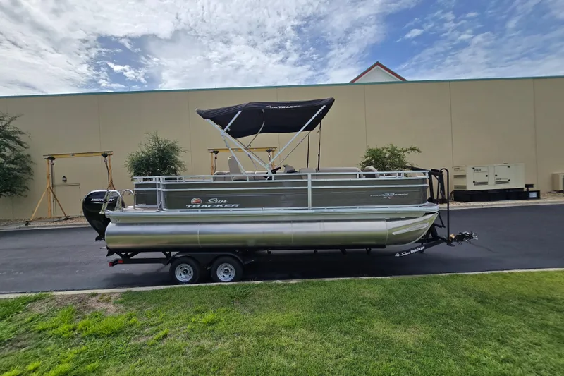 Slide: The Image of 2026 Sun Tracker Sportfish 24 XP3 pontoon boat on trailer, parked outdoors. - 88