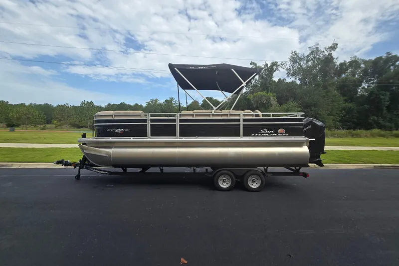 Slide: The Image of 2026 Sun Tracker Sportfish 24 XP3 pontoon boat on trailer, parked outdoors. - 86