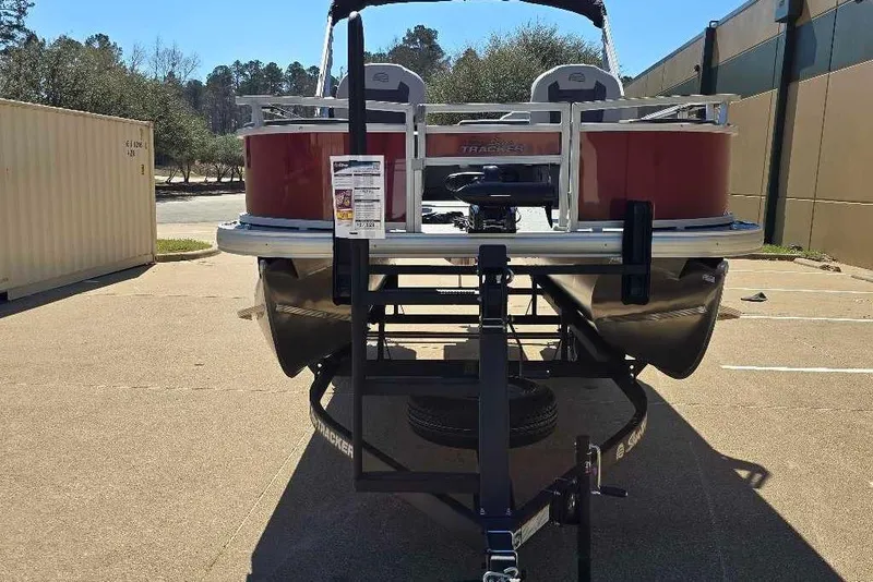 Slide: The Image of 2026 Sun Tracker Bass Buggy 18 DLX pontoon boat on trailer, parked outdoors. - 6