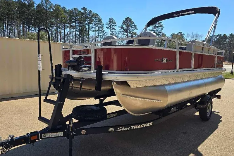 Slide: The Image of 2026 Sun Tracker Bass Buggy 18 DLX pontoon boat on trailer, parked outdoors. - 7