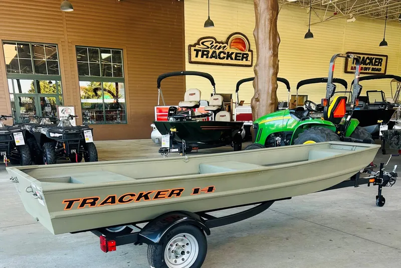 The Image of 2026 Tracker Grizzly 14 Jon boat displayed at dealership with tractors and ATVs. - 0