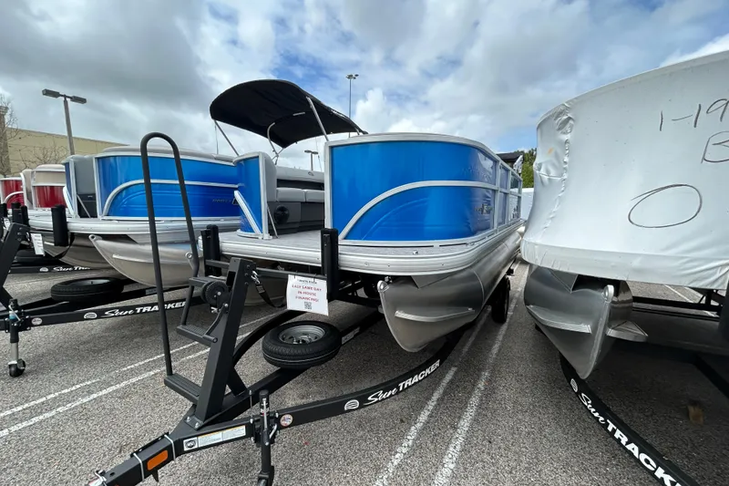 The Image of 2026 Sun Tracker Party Barge 16 DLX pontoon boat displayed in a parking lot. - 0