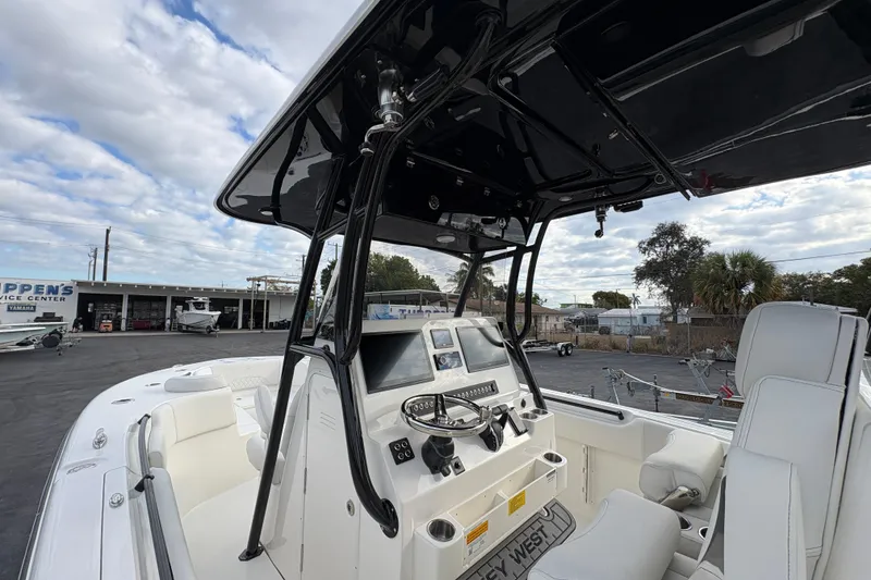 Slide: The Image of 2026 Key West 291 FS boat interior with steering console and seating, under a cloudy sky. - 4