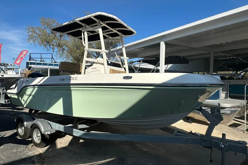 Slide: The Image of 2026 Bayliner Trophy T20CC boat on trailer, parked outdoors under clear blue sky. - 15
