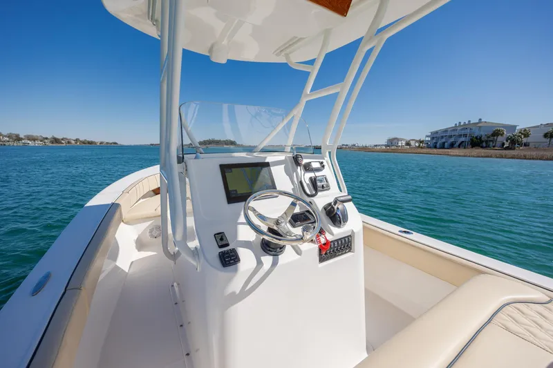 Slide: The Image of 2022 Vanquish Bristol Harbor 23 CC boat on calm water, featuring modern helm controls. - 14