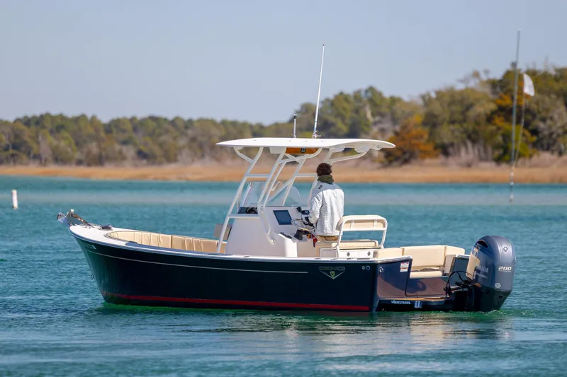 Slide: The Image of 2022 Vanquish Bristol Harbor 23 CC boat on calm water, with a person at the helm. - 5