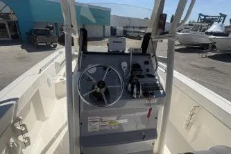 Slide: The Image of 2023 Trophy T22 boat console with steering wheel and controls, docked outdoors. - 4