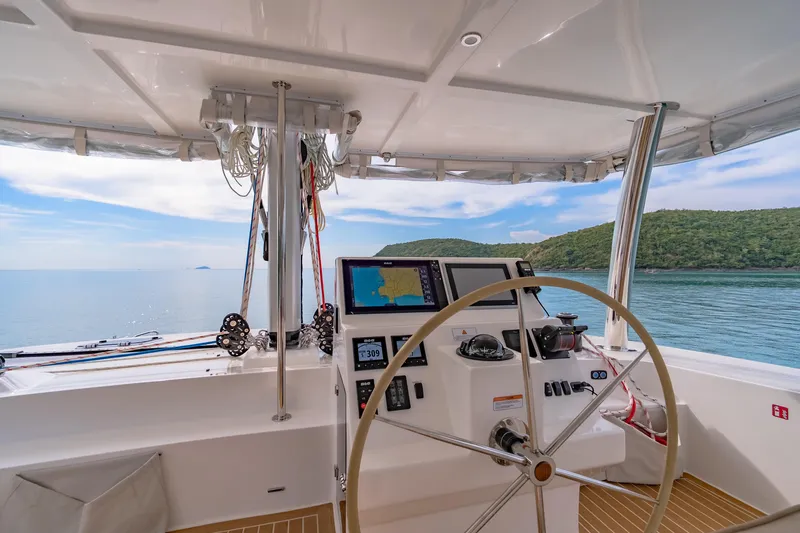 Slide: The Image of Helm of 2026 Island Spirit 525E catamaran with navigation equipment, overlooking serene ocean and island. - 22