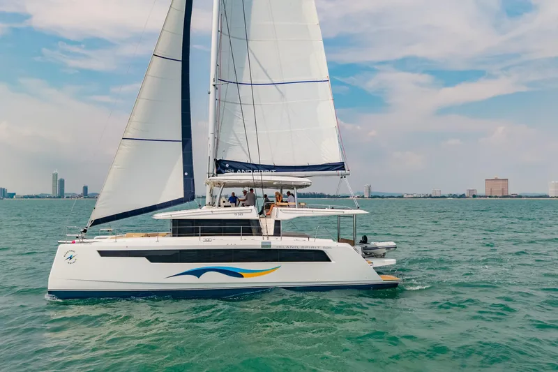 Slide: The Image of Sailing catamaran Island Spirit 525E 2026 on open water with city skyline backdrop. - 3
