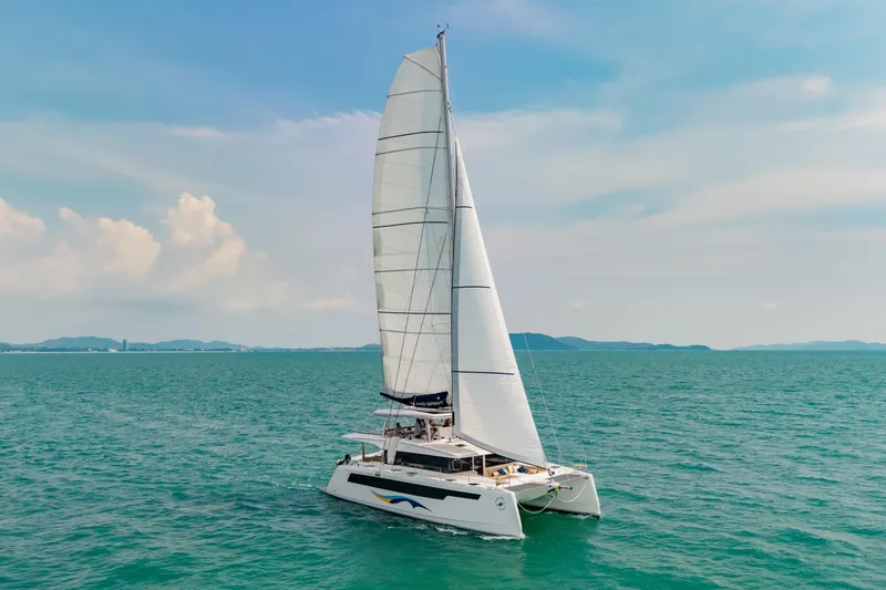 Slide: The Image of 2026 Island Spirit 525E catamaran sailing on open sea under clear blue sky. - 38