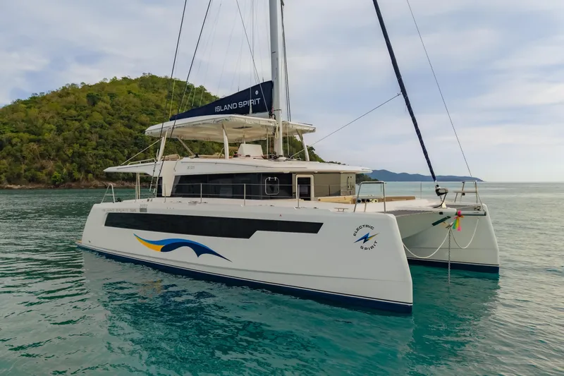 Slide: The Image of 2026 Island Spirit 525E catamaran sailing near lush island, calm turquoise waters. - 39