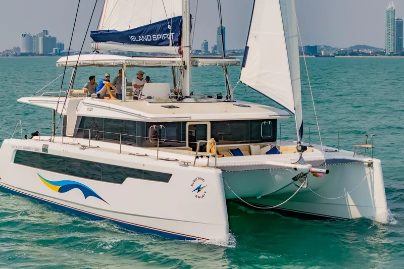 Slide: The Image of 2026 Island Spirit 525E catamaran sailing on turquoise waters near a city skyline. - 4
