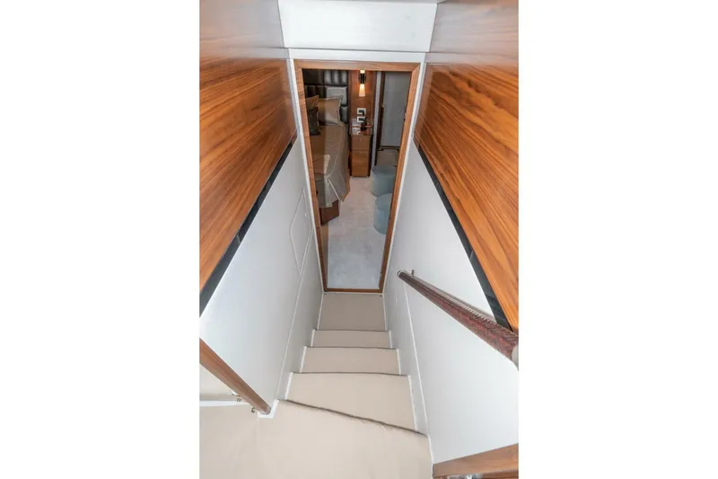 Slide: The Image of Stairway inside 2025 Viking 90 Convertible yacht, featuring wood paneling and modern design. - 44