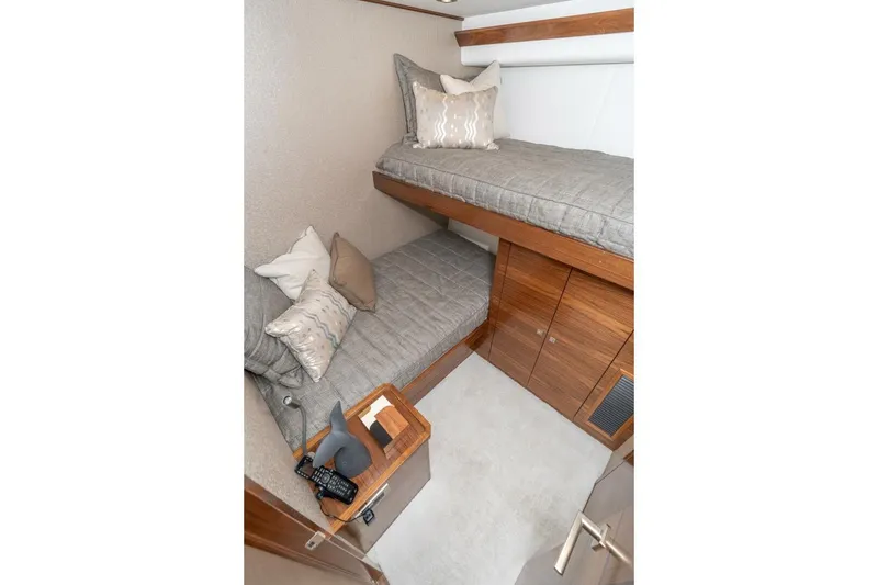 Slide: The Image of 2025 Viking 90 Convertible yacht cabin with bunk beds and wooden cabinetry. - 49