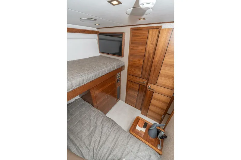 Slide: The Image of 2025 Viking 90 Convertible yacht interior with wooden cabinetry and bunk beds. - 50