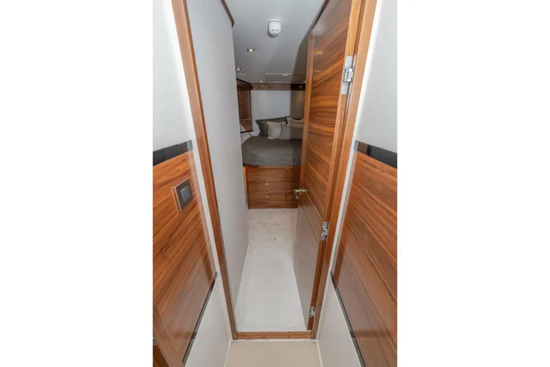 Slide: The Image of Interior hallway of 2025 Viking 90 Convertible yacht with wood paneling and cozy bedroom. - 51