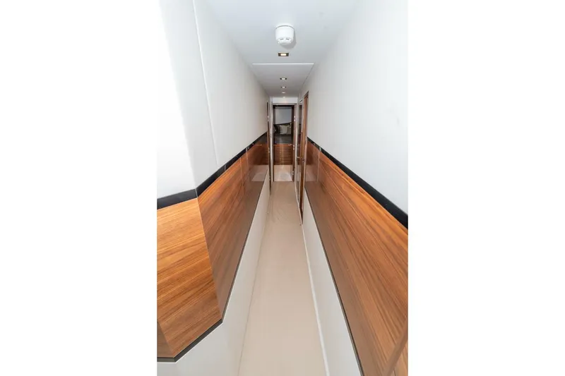 Slide: The Image of Narrow hallway with wood paneling inside 2025 Viking 90 Convertible yacht. - 57