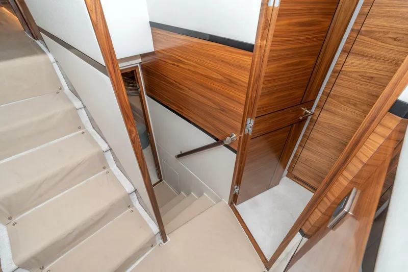 Slide: The Image of Interior of 2025 Viking 90 Convertible yacht with wooden finishes and carpeted stairs. - 58