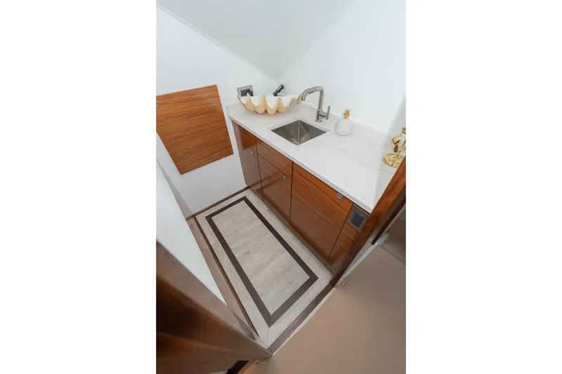 Slide: The Image of Compact kitchen area in 2025 Viking 90 Convertible yacht with modern sink and wooden cabinetry. - 60