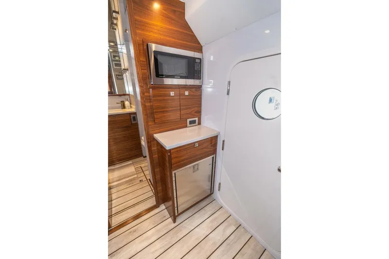 Slide: The Image of 2025 Viking 90 Convertible yacht interior with microwave, wooden cabinetry, and modern design. - 68