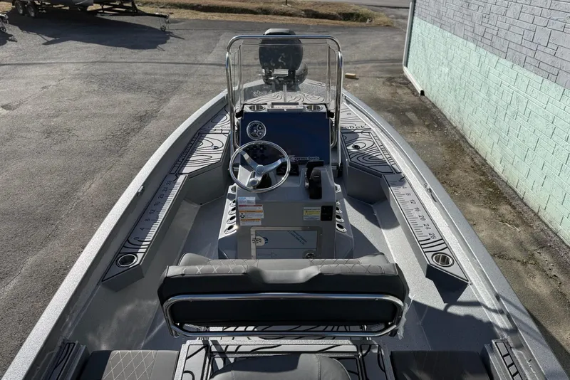 Slide: The Image of 2026 Xpress H20B Bay boat interior with steering console and seating, parked outdoors. - 10