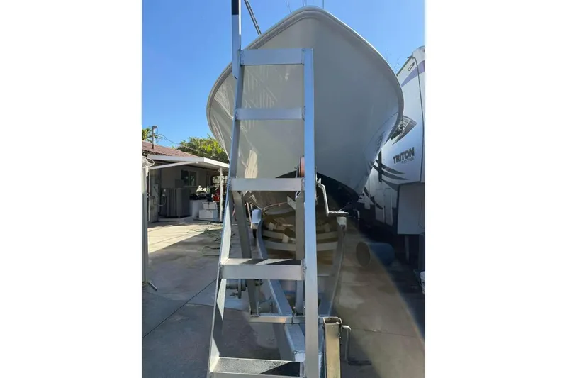 Slide: The Image of 2022 Contender 35 ST boat on trailer with ladder, parked outdoors. - 15