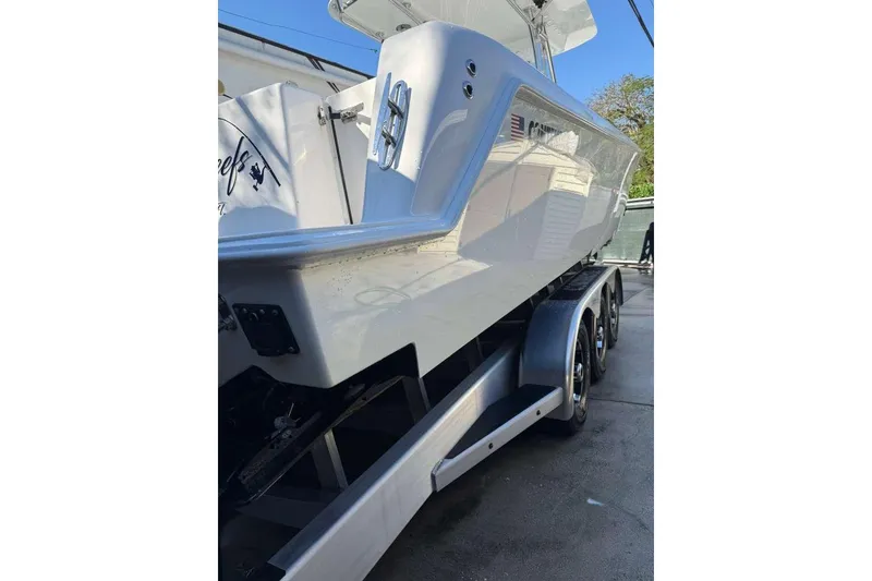 Slide: The Image of 2022 Contender 35 ST boat on trailer, side view, showcasing sleek design and triple-axle support. - 24