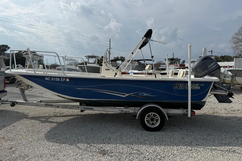 Slide: The Image of 2017 Carolina Skiff 218 DLV boat on trailer, blue hull, parked outdoors. - 12